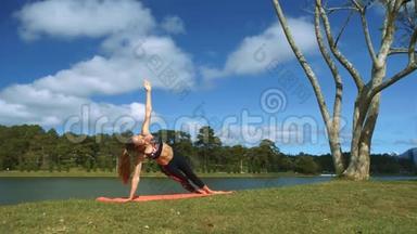 女孩在湖岸用手臂和腿支撑瑜伽姿势